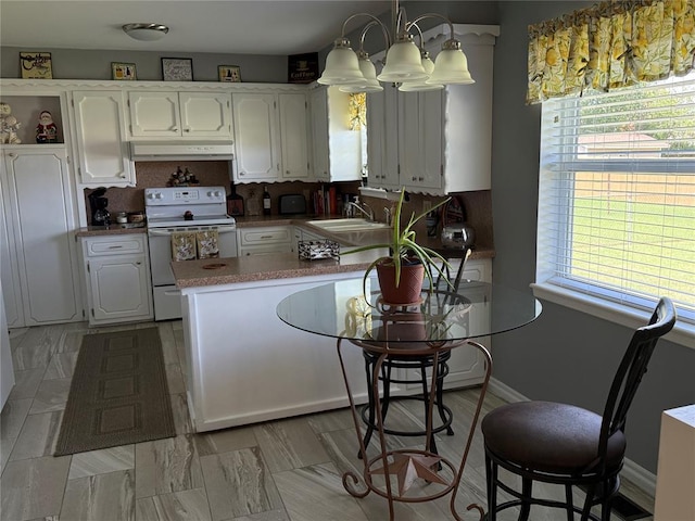 1901 N Oklahoma Ave, Shawnee, OK 74804 - kitchen featuring electric range, white cabinetry, a peninsula, and under cabinet range hood