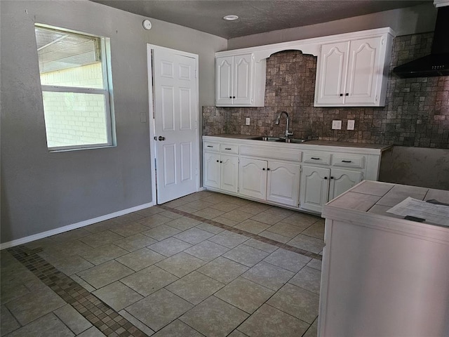 4001 SE 22nd St, Del City, OK 73115 - kitchen featuring wall chimney range hood, white cabinets, tasteful backsplash, and light tile patterned flooring