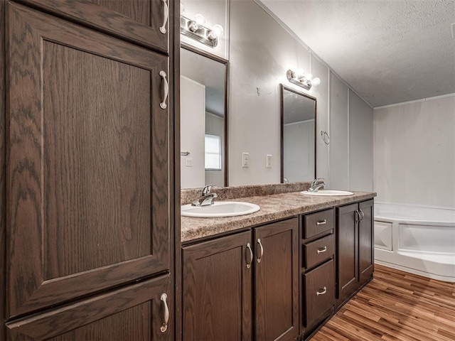 355370 E 970th Rd, Sparks, OK 74869 - bathroom with double vanity, wood finished floors, a garden tub, a textured ceiling, and a decorative wall