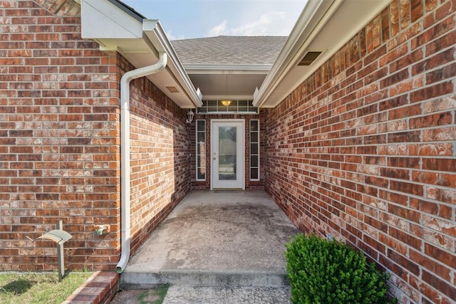 12417 Sussex Dr, Oklahoma City, OK 73130 - doorway to property featuring brick siding and a shingled roof