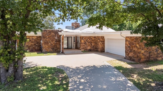 2104 Brookhaven Dr, Edmond, OK 73034 - view of front of house featuring stone siding, a chimney, and a garage