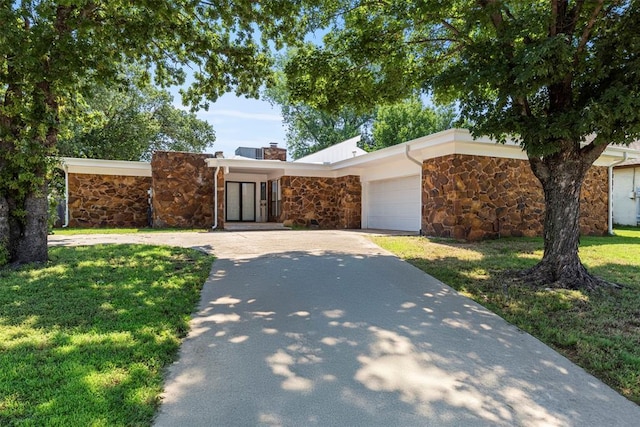 2104 Brookhaven Dr, Edmond, OK 73034 - mid-century modern home featuring stone siding, driveway, a front yard, an attached garage, and a chimney
