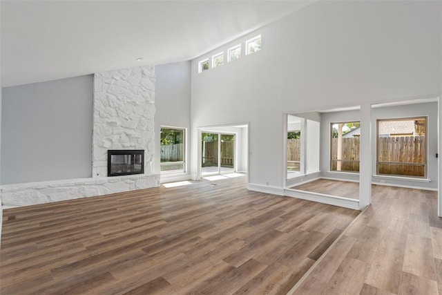2104 Brookhaven Dr, Edmond, OK 73034 - unfurnished living room featuring healthy amount of natural light, wood finished floors, a stone fireplace, and a high ceiling