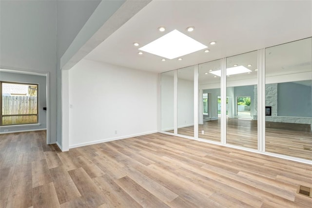 2104 Brookhaven Dr, Edmond, OK 73034 - unfurnished room with plenty of natural light, a skylight, light wood-type flooring, recessed lighting, and a fireplace
