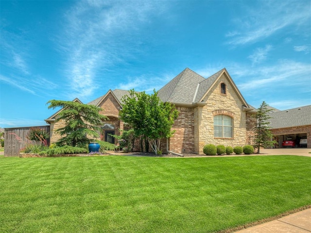 16208 Windrush Pl, Edmond, OK 73013 - view of front facade with stone siding, a front yard, and a shingled roof