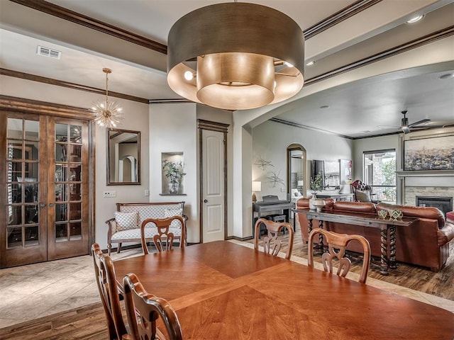 16208 Windrush Pl, Edmond, OK 73013 - dining room with ornamental molding, a ceiling fan, a stone fireplace, and arched walkways