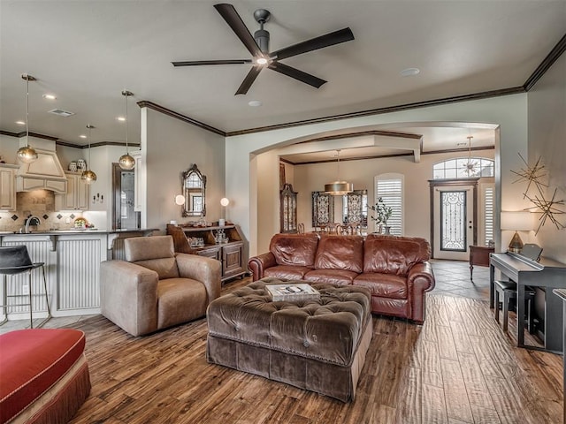 16208 Windrush Pl, Edmond, OK 73013 - living room featuring arched walkways, ornamental molding, a ceiling fan, and wood finished floors