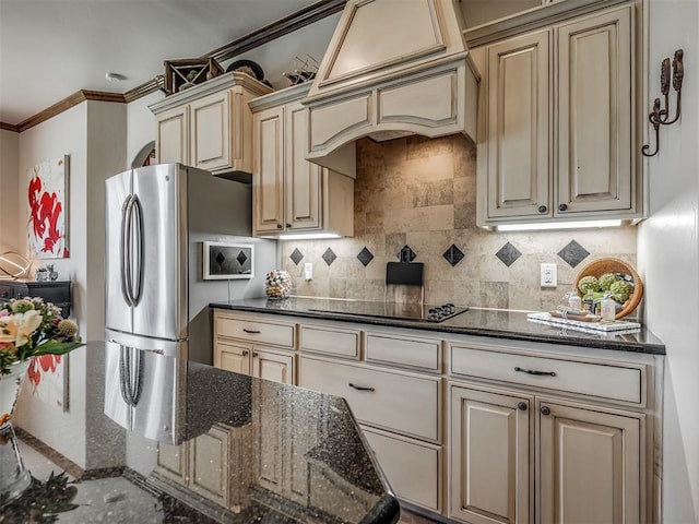 16208 Windrush Pl, Edmond, OK 73013 - kitchen with freestanding refrigerator, cream cabinetry, crown molding, black electric stovetop, and tasteful backsplash