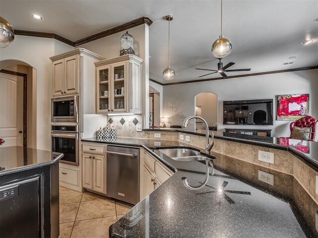 16208 Windrush Pl, Edmond, OK 73013 - kitchen featuring stainless steel appliances, cream cabinets, crown molding, arched walkways, and open floor plan