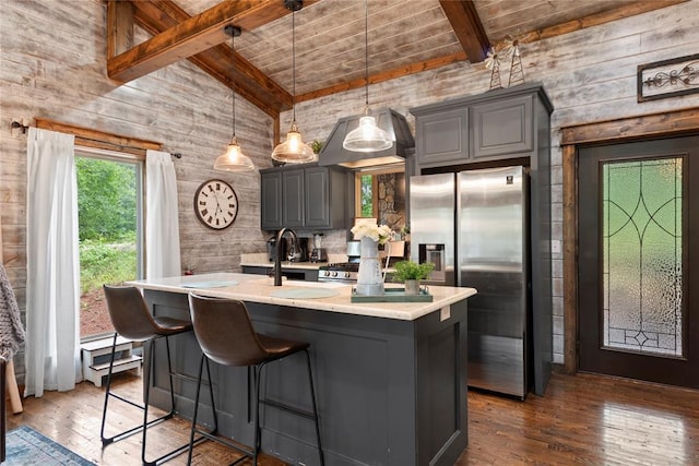 180 Black Jack Trl, Hochatown, OK 74728 - kitchen featuring stainless steel refrigerator with ice dispenser, gray cabinetry, wooden walls, hardwood / wood-style flooring, and a kitchen island with sink