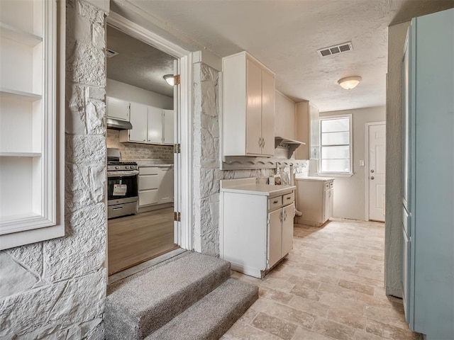 118 W Marshall Dr, Oklahoma City, OK 73110 - kitchen featuring gas range, a textured ceiling, under cabinet range hood, light countertops, and tasteful backsplash