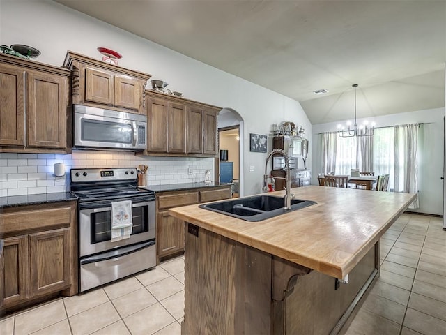 749 Dana Dr, Yukon, OK 73099 - kitchen with stainless steel appliances, light tile patterned floors, wood counters, lofted ceiling, and decorative backsplash