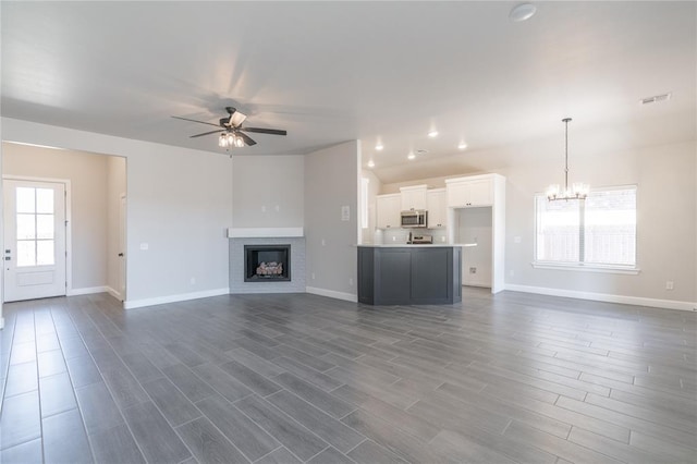 1224 Colonial Ave, Tuttle, OK 73089 - unfurnished living room featuring a ceiling fan, a chandelier, vaulted ceiling, dark wood-style flooring, and a fireplace