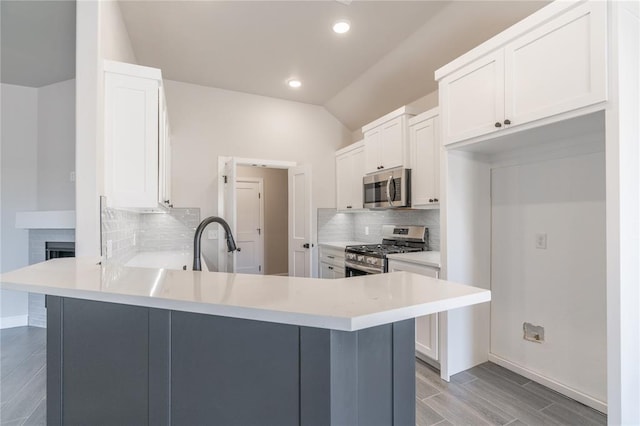 1224 Colonial Ave, Tuttle, OK 73089 - kitchen featuring appliances with stainless steel finishes, a peninsula, decorative backsplash, white cabinetry, and light countertops