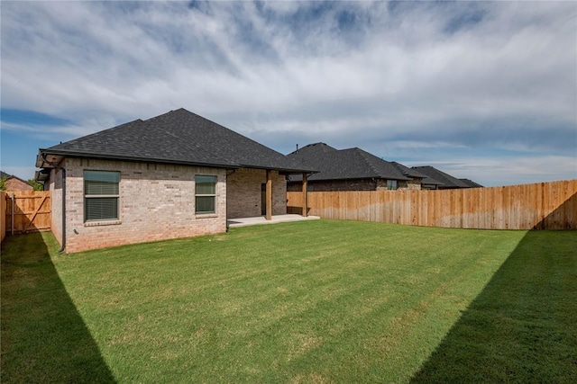 1224 Colonial Ave, Tuttle, OK 73089 - back of property featuring a shingled roof, a fenced backyard, a patio, and brick siding
