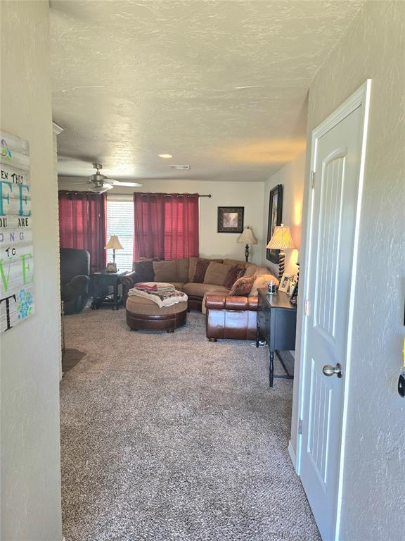 2015 Willard Dr, Altus, OK 73521 - carpeted living area with a textured ceiling and ceiling fan