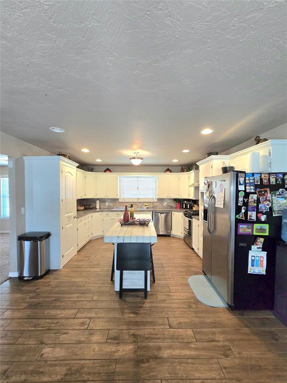 2015 Willard Dr, Altus, OK 73521 - kitchen with stainless steel appliances, dark wood finished floors, white cabinets, recessed lighting, and light countertops