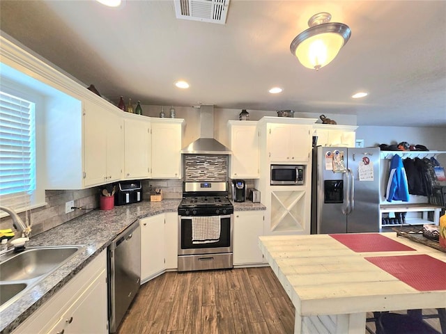 2015 Willard Dr, Altus, OK 73521 - kitchen featuring wall chimney exhaust hood, appliances with stainless steel finishes, white cabinets, decorative backsplash, and recessed lighting
