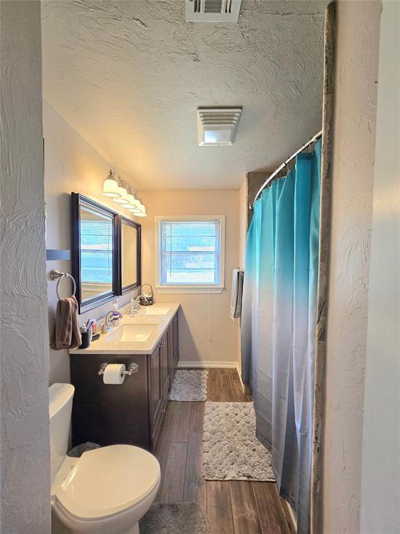 2015 Willard Dr, Altus, OK 73521 - bathroom with wood finished floors, vanity, curtained shower, and a textured ceiling