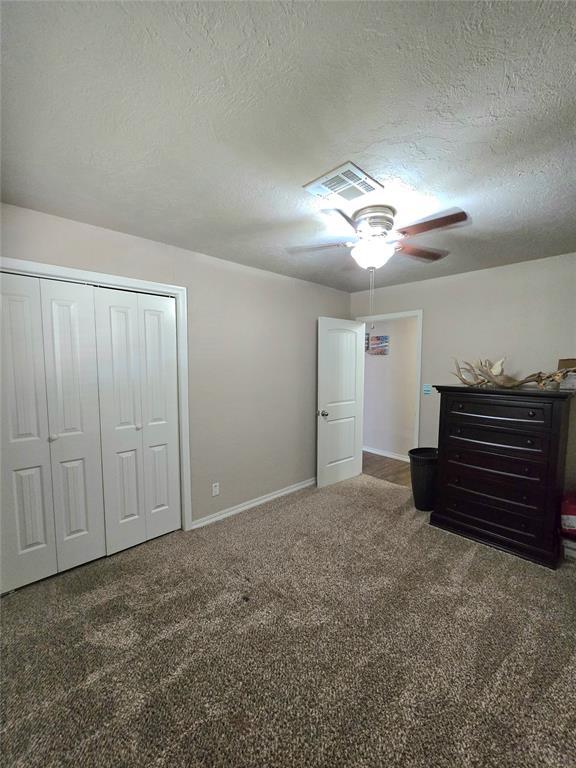 2015 Willard Dr, Altus, OK 73521 - unfurnished bedroom with carpet floors, a textured ceiling, a closet, and ceiling fan