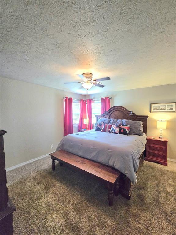 2015 Willard Dr, Altus, OK 73521 - bedroom featuring carpet floors, a textured ceiling, and a ceiling fan