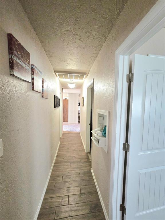 2015 Willard Dr, Altus, OK 73521 - hallway with a textured wall, dark wood-style flooring, and a textured ceiling