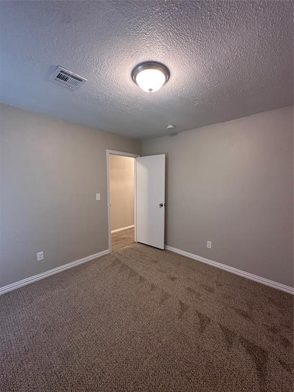 8317 NW 85th St, Oklahoma City, OK 73132 - empty room with carpet and a textured ceiling
