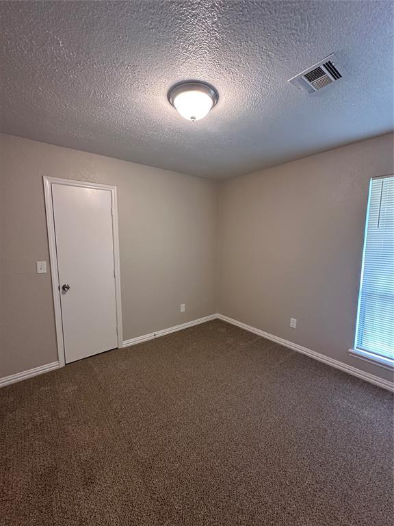 8317 NW 85th St, Oklahoma City, OK 73132 - unfurnished room featuring dark carpet and a textured ceiling