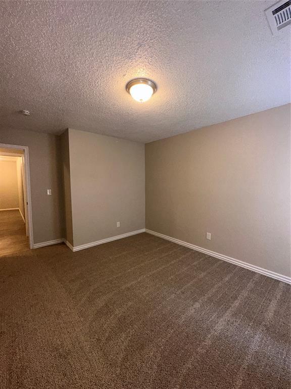 8317 NW 85th St, Oklahoma City, OK 73132 - unfurnished room featuring dark colored carpet and a textured ceiling