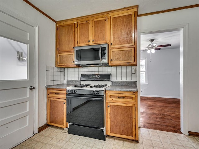 2713 S Glenn Ave, Del City, OK 73115 - kitchen with stainless steel microwave, gas range, backsplash, a ceiling fan, and brown cabinetry
