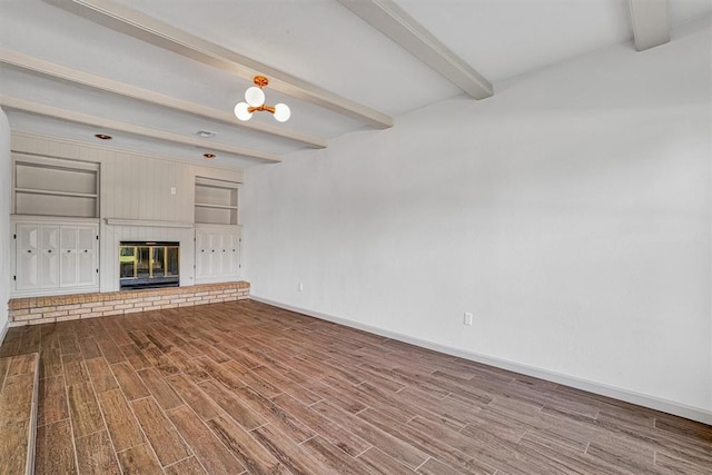 1608 Truman Dr, Altus, OK 73521 - unfurnished living room featuring beam ceiling, wood finished floors, and a brick fireplace