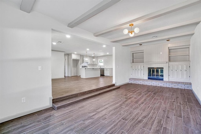 1608 Truman Dr, Altus, OK 73521 - unfurnished living room with dark wood finished floors, beamed ceiling, a brick fireplace, recessed lighting, and a chandelier