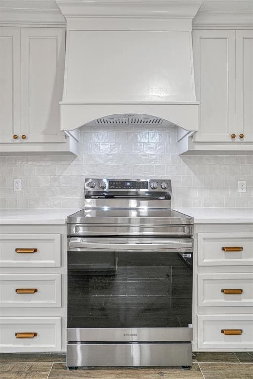 1608 Truman Dr, Altus, OK 73521 - kitchen with stainless steel range with electric cooktop, custom exhaust hood, light countertops, and tasteful backsplash