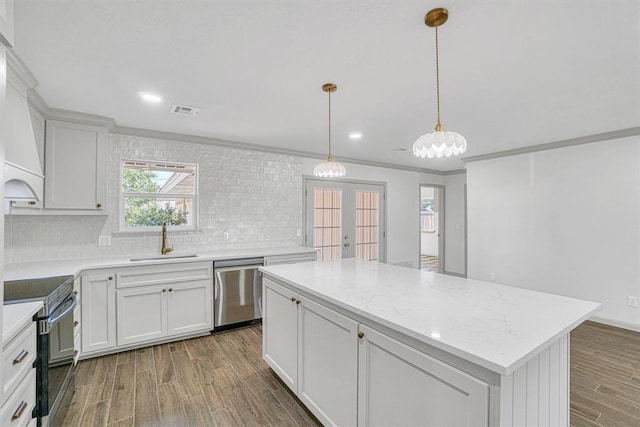 1608 Truman Dr, Altus, OK 73521 - kitchen with appliances with stainless steel finishes, backsplash, wood finished floors, a kitchen island, and white cabinets
