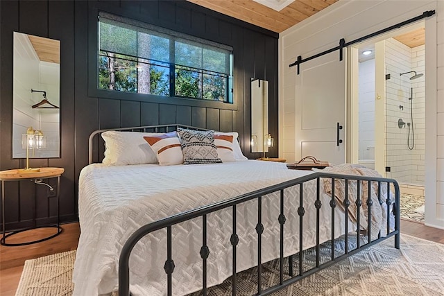 42 Hickory Ridge Rd, Broken Bow, OK 74728 - bedroom featuring a barn door, light wood finished floors, wood ceiling, and wooden walls