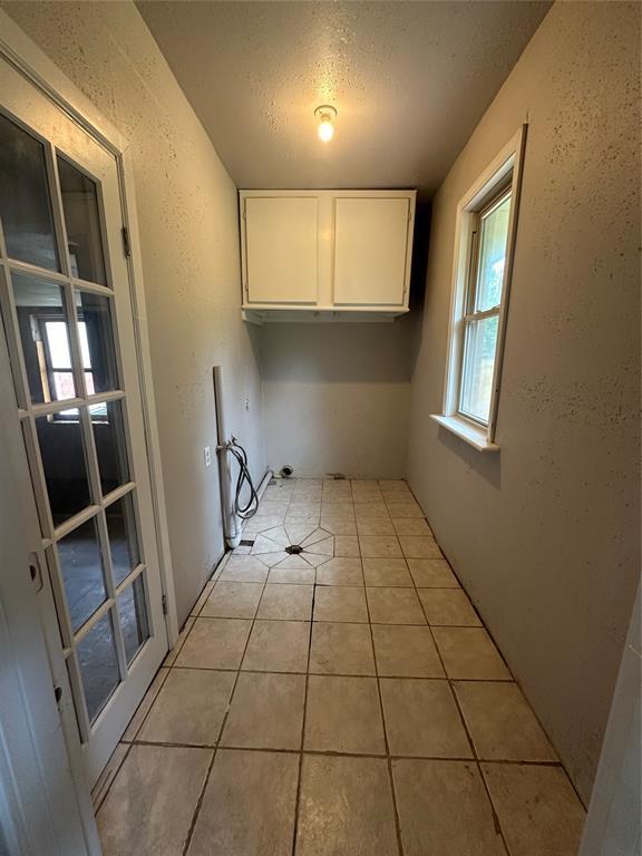 112 Burk Way, Del City, OK 73115 - laundry room with cabinet space, hookup for a washing machine, a textured ceiling, light tile patterned floors, and a textured wall