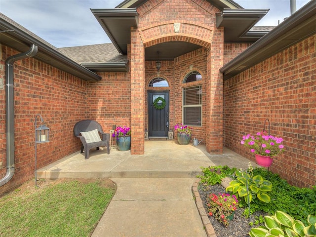 2108 Mulberry Creek Ave, Yukon, OK 73099 - doorway to property with brick siding, a shingled roof, and a patio