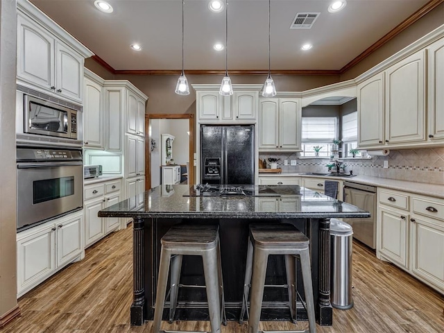 2108 Mulberry Creek Ave, Yukon, OK 73099 - kitchen with black appliances, a breakfast bar area, ornamental molding, light wood-style flooring, and tasteful backsplash