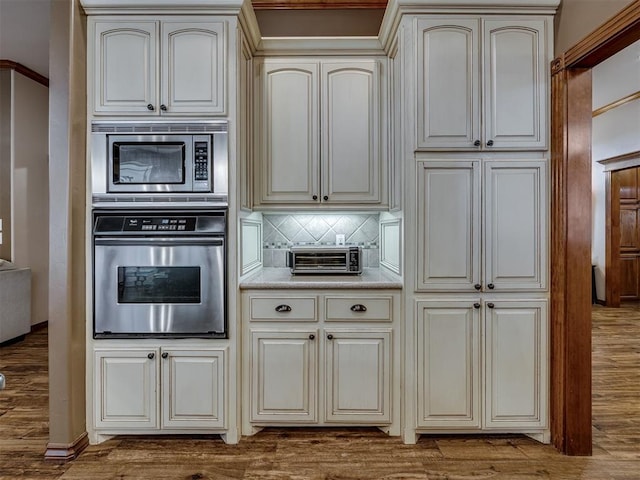 2108 Mulberry Creek Ave, Yukon, OK 73099 - kitchen featuring appliances with stainless steel finishes, cream cabinets, decorative backsplash, and wood finished floors