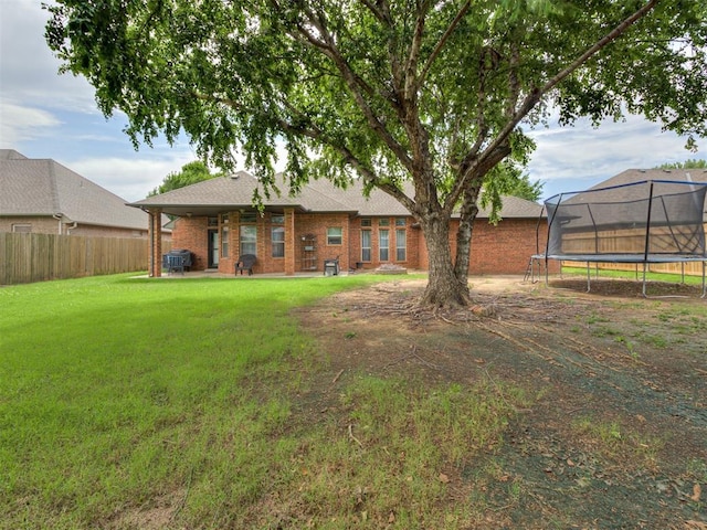 2108 Mulberry Creek Ave, Yukon, OK 73099 - back of property featuring a trampoline, brick siding, and a shingled roof