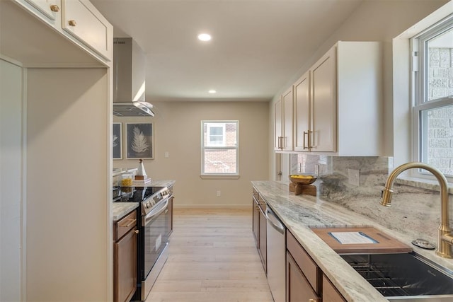 1109 NE 17th St, Oklahoma City, OK 73111 - kitchen with appliances with stainless steel finishes, wall chimney range hood, light wood-type flooring, recessed lighting, and light stone countertops