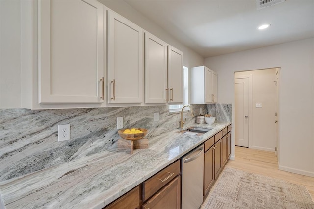 1109 NE 17th St, Oklahoma City, OK 73111 - kitchen featuring stainless steel dishwasher, light stone counters, decorative backsplash, light wood-style floors, and white cabinetry