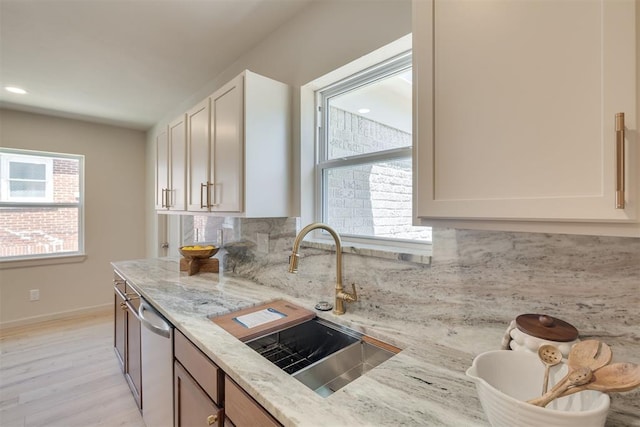 1109 NE 17th St, Oklahoma City, OK 73111 - kitchen with stainless steel dishwasher, tasteful backsplash, light stone counters, light wood-type flooring, and recessed lighting