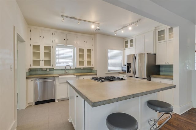 1134 NW 40th St, Oklahoma City, OK 73118 - kitchen with appliances with stainless steel finishes, a center island, decorative backsplash, white cabinetry, and glass insert cabinets