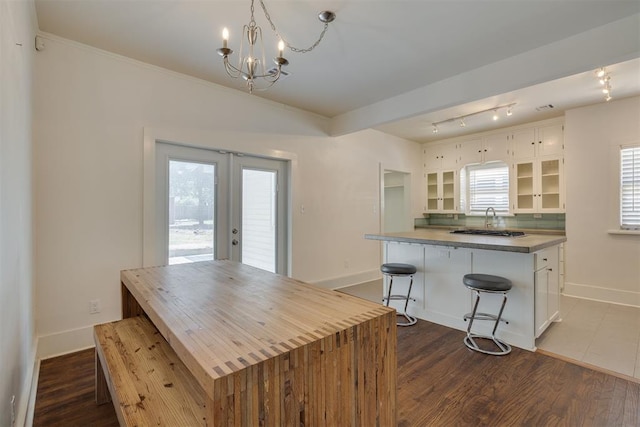 1134 NW 40th St, Oklahoma City, OK 73118 - kitchen featuring white cabinets, a chandelier, glass insert cabinets, french doors, and dark wood-type flooring