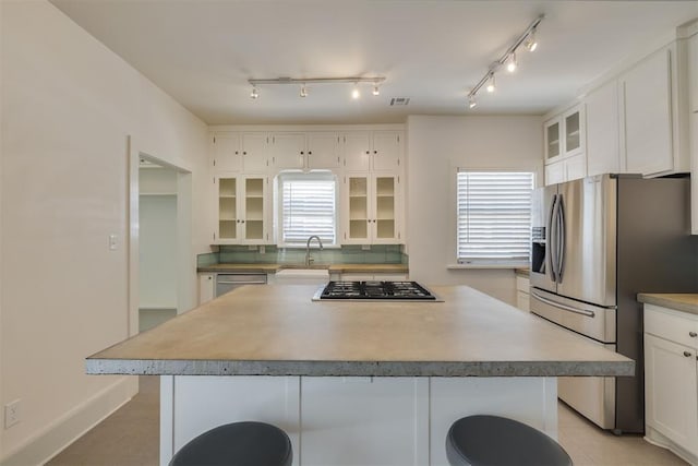 1134 NW 40th St, Oklahoma City, OK 73118 - kitchen featuring stainless steel appliances, a kitchen island, glass insert cabinets, white cabinets, and a kitchen bar