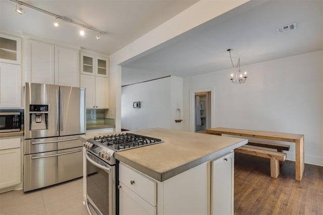 1134 NW 40th St, Oklahoma City, OK 73118 - kitchen featuring appliances with stainless steel finishes, a chandelier, white cabinets, a center island, and glass insert cabinets