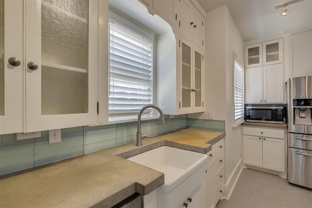1134 NW 40th St, Oklahoma City, OK 73118 - kitchen with stainless steel appliances, white cabinetry, light tile patterned floors, glass insert cabinets, and tasteful backsplash