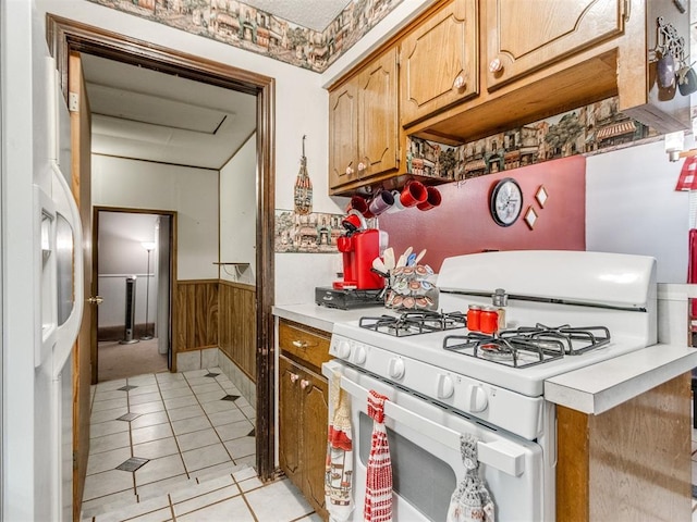 3900 Chetwood Dr, Del City, OK 73115 - kitchen with white gas range oven, a wainscoted wall, light countertops, light tile patterned floors, and wood walls