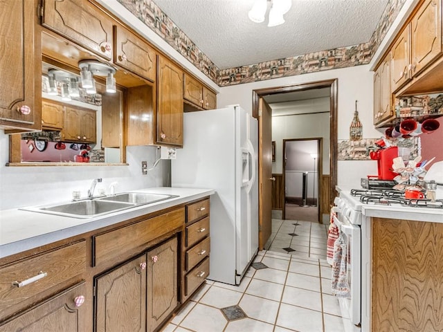 3900 Chetwood Dr, Del City, OK 73115 - kitchen with white appliances, a textured ceiling, light tile patterned floors, light countertops, and brown cabinetry